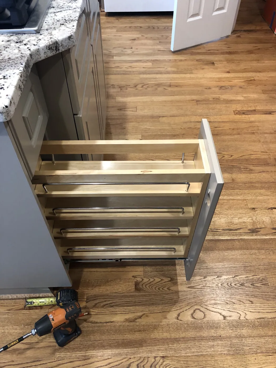A pull-out cabinet being installed beside a granite counter